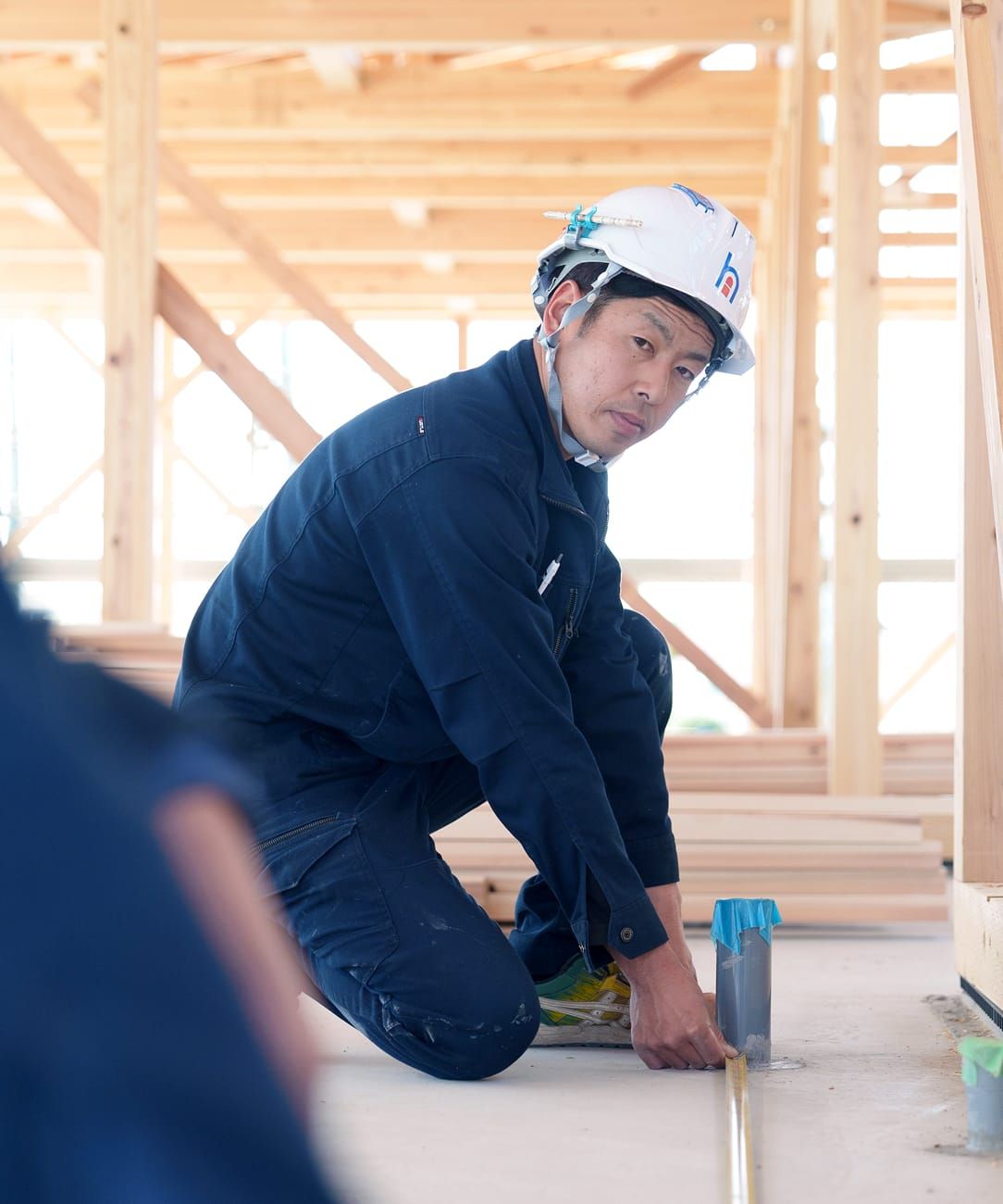 建築現場でメジャーを使用し正確な計測作業を行うヒタチ設備の施工スタッフ。
