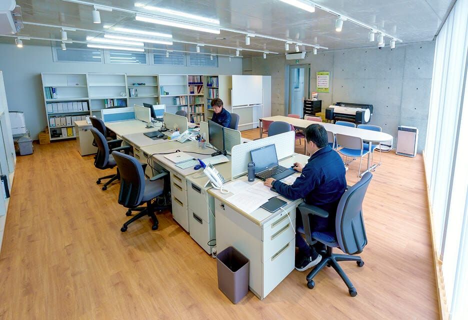整理整頓された株式会社ヒタチ設備の広々としたオフィスで、パソコン作業に集中する社員。