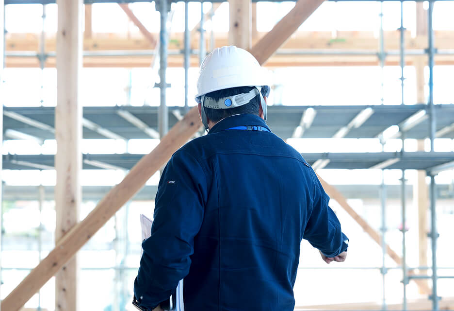 建設途中の現場で足場や骨組みを確認し、施工管理を行う作業員の姿